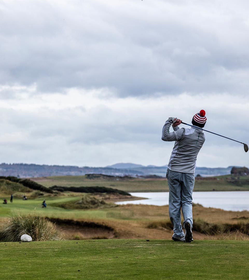 A golfer taking a swing on Castle Stuart golf course