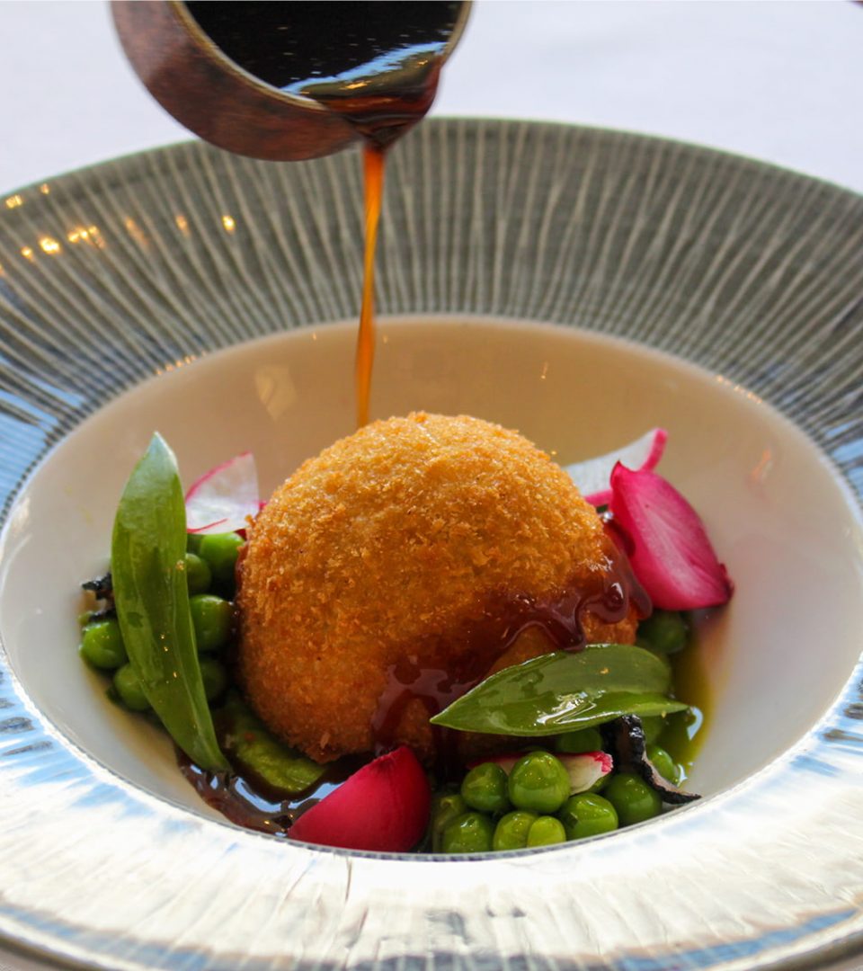 jus being poured on lamb shoulder croquette