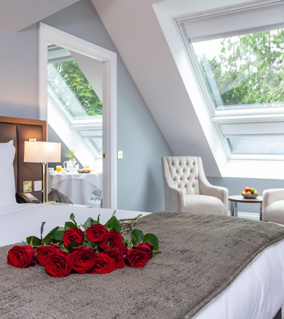 a dozen roses sitting on hotel suite bed