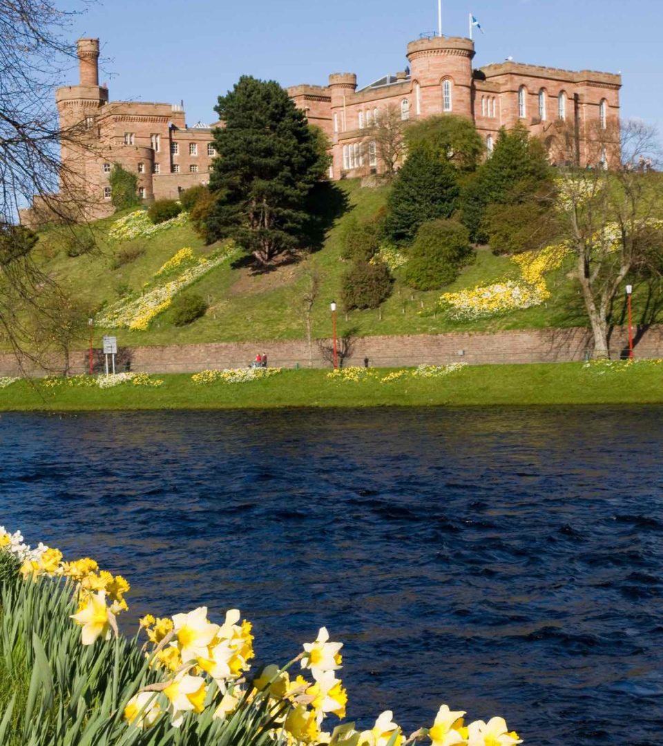 Inverness Castle on a sunny day with daffodils by the river