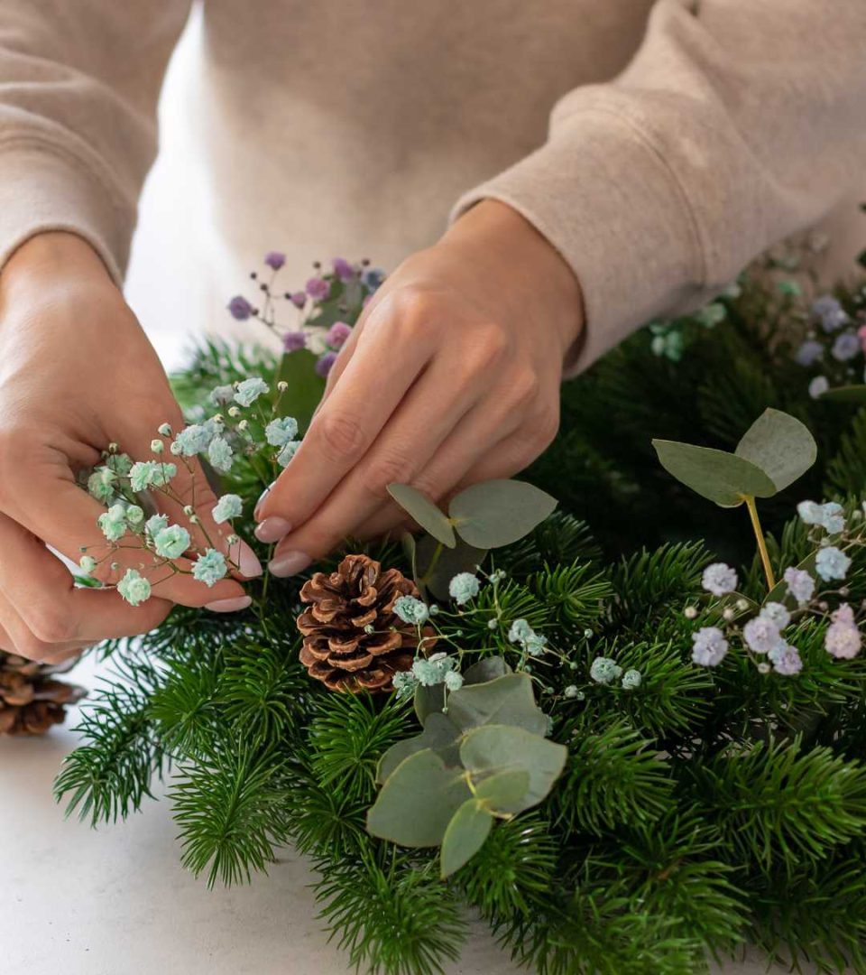 Person putting final decoration on a Christmas wreath at Ness Walk