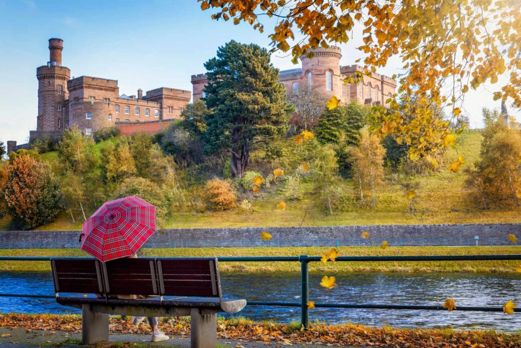 Woman with tartan umbrella looking at Inverness Castle