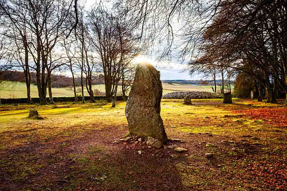 Standing stone with sun behind it at Clava Cairns.