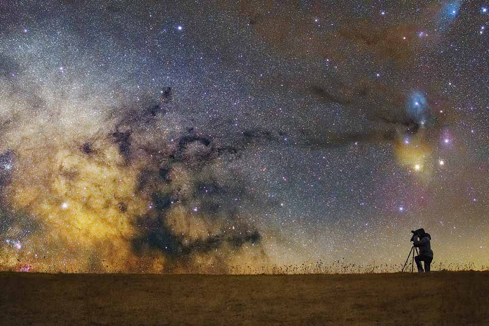 A person taking a photo of the Milky Way at night.