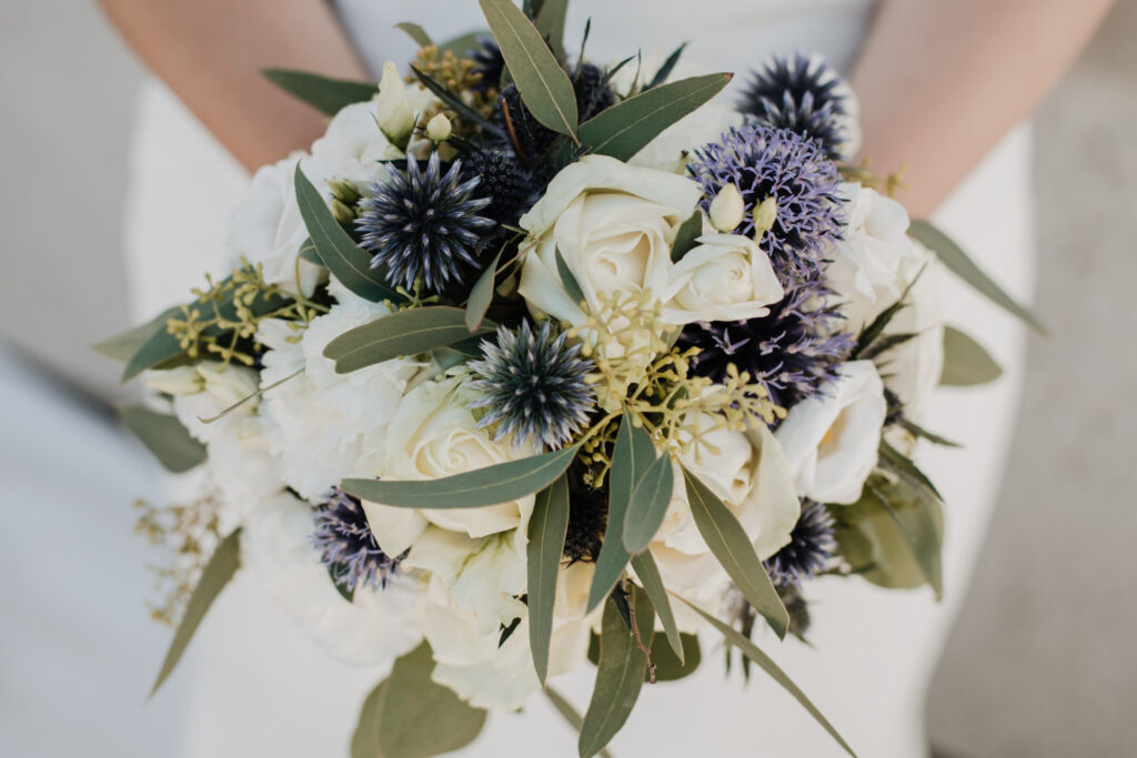 Bride's bouquet with white roses and blue thistles